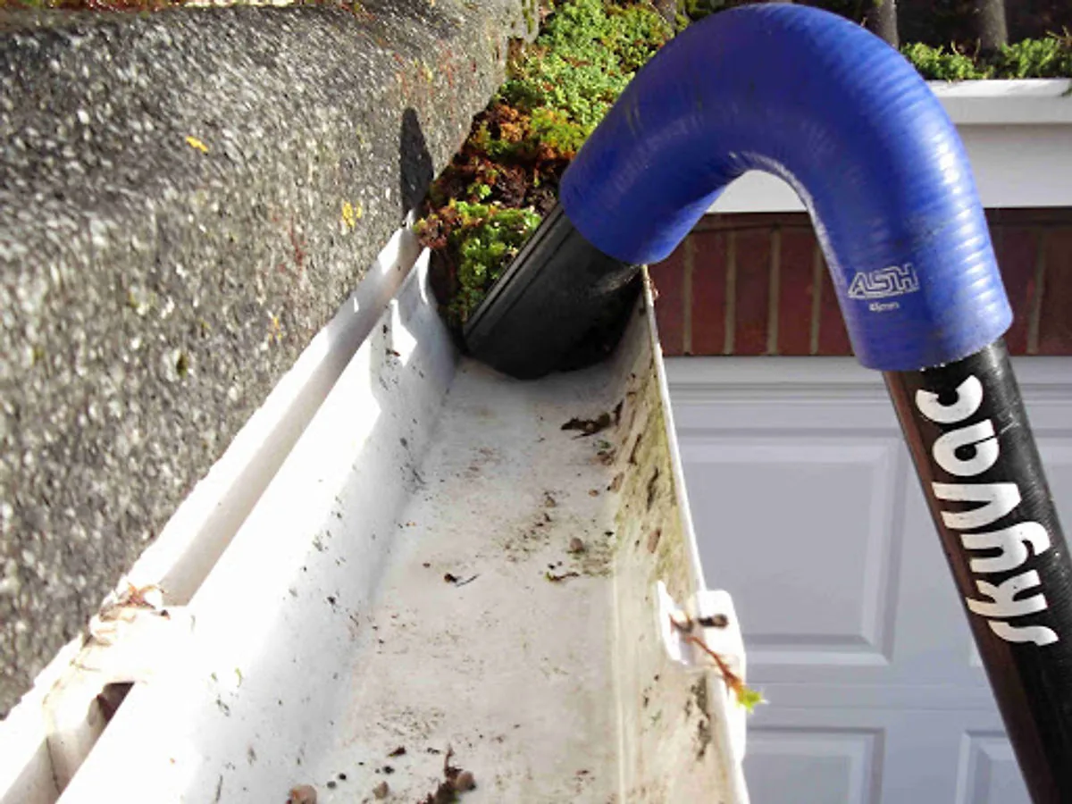 Specialist gutter vacuum equipment being used to clear a gutter
