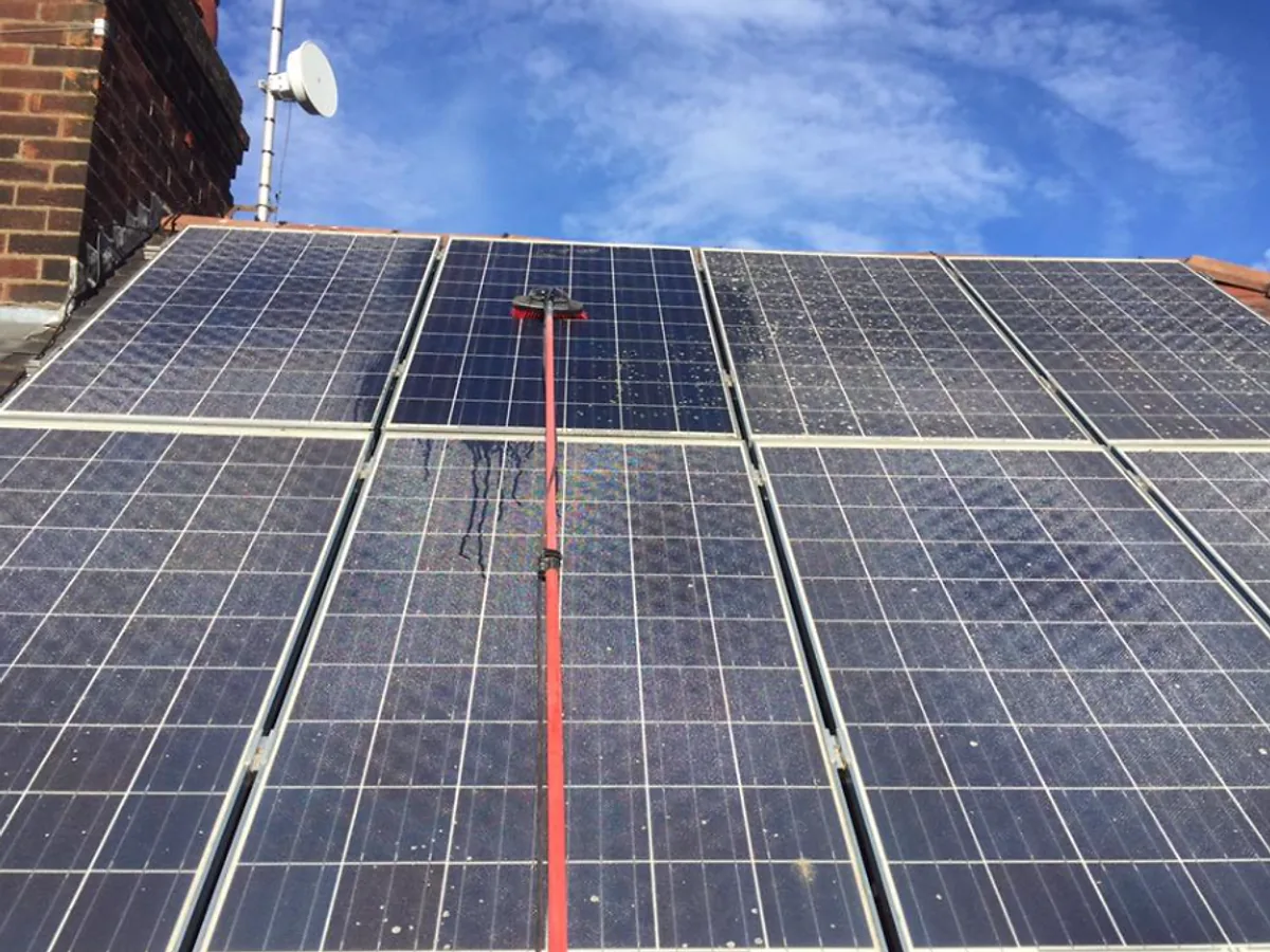 Solar panels being cleaned with specialist water-fed equipment
